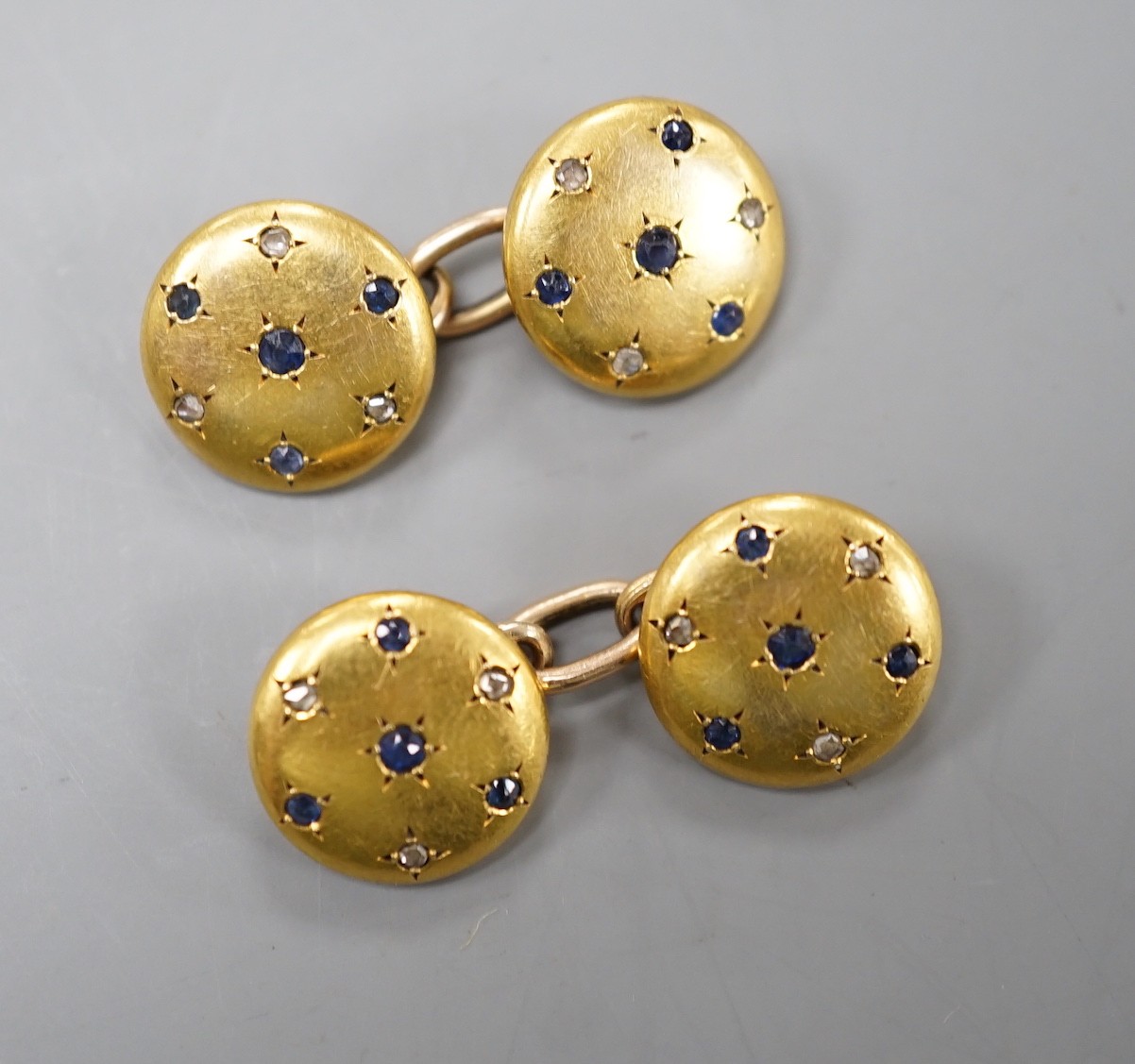 A pair of yellow metal, sapphire and diamond chip set circular cufflinks, diameter 12mm, gross weight 8.6 grams.